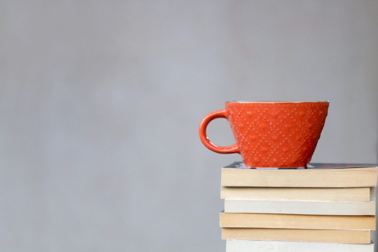 Where will your reading list take you? Image of a pile of books topped by a coffee mug. Image: Shutterstock
